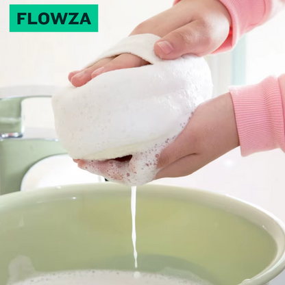 Mains tenant une éponge luffa bio blanche et mousseuse au-dessus d'un bol vert pâle